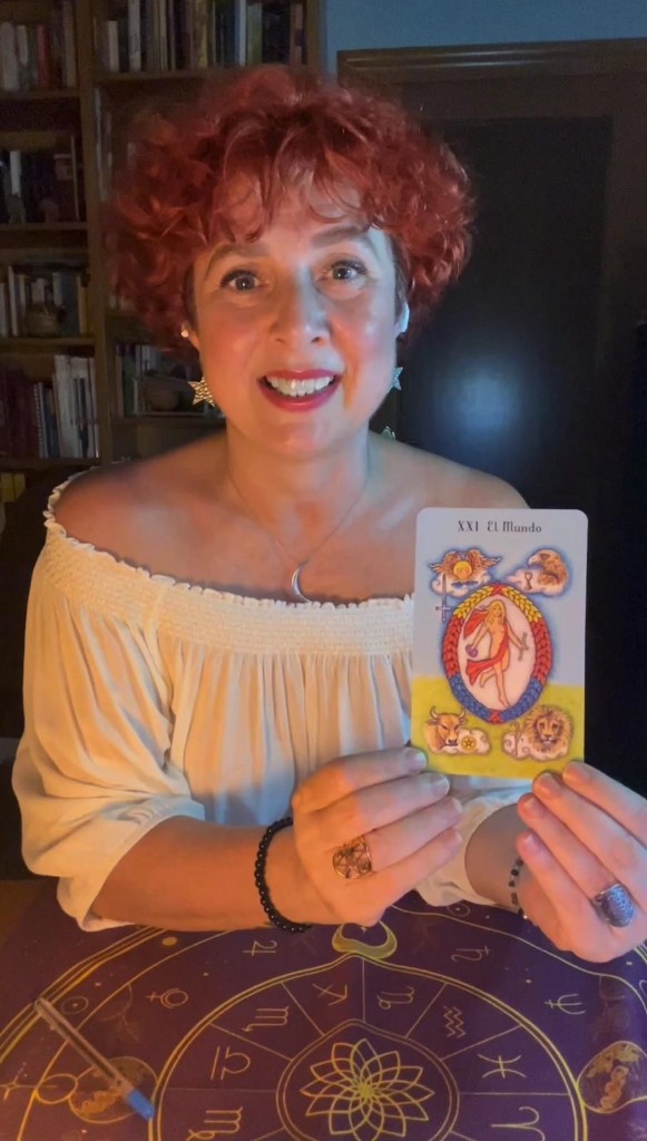 Marisa Le Fay sosteniendo la carta El Mundo del tarot
